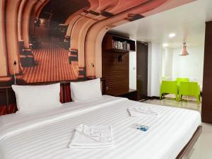 a bedroom with a large white bed with green chairs at The Color Kata in Kata Beach