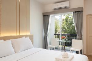 a bedroom with a bed and a balcony with a table at Riski Residence Ngamwongwan in Nonthaburi