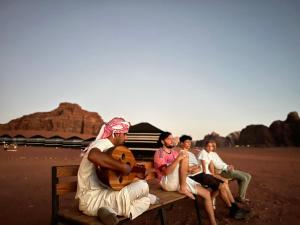 un grupo de personas sentadas en un banco en el desierto en Desert Bird Camp, en Wadi Rum