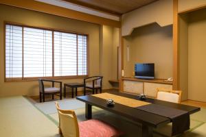 a living room with a table and chairs and a television at Hotel Shirakawa Yunokura in Nikko