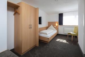 ein Schlafzimmer mit einem Bett, einem Schrank und einem Fenster in der Unterkunft Landhotel Sonnenhalde in Bad Boll