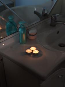 Duas velas estão sentadas num lavatório da casa de banho. em Primoula Grammou 1450 em Nea Kotili