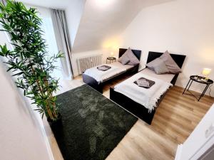 ein Wohnzimmer mit 2 Betten und Topfpflanzen in der Unterkunft ND Hotels & Apartment Düsseldorf in Düsseldorf