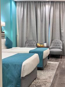 a bedroom with two beds and two chairs at Howard Johnson Bur Dubai in Dubai