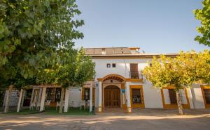 a white building with trees in front of it at Hotel del Carmen in Prado del Rey