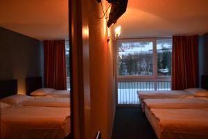 a hotel room with two beds and a window at Hotel Les Rives Du Doubs in Les Brenets