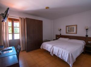 a bedroom with a bed and a desk and a television at Hotel del Carmen in Prado del Rey +13 photos