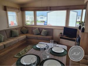 a living room with a table and a couch at The Meadows 34 - Golden Palm Resort, pet friendly, WiFi & bed linen - Meadow Lakes Caravan & Lodge Hire in Chapel Saint Leonards
