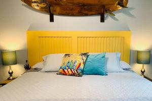 a bed with two pillows on it with two lamps at Puolani Iki-Sweet lil cottage near National Park in Volcano