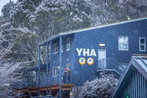 a group of people standing on the balcony of a blue house at YHA Thredbo in Thredbo