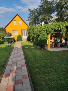 un patio trasero con una casa amarilla y un patio en La Prietenicu, en Murighiol