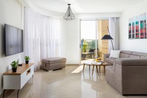een woonkamer met een bank en een tafel bij YalaRent Golf Residence 3BR apt in luxury complex with pool in Eilat