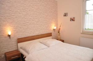 a bedroom with a white bed and a brick wall at Ferienwohnungen Appartements - Ferienhaus Müritzstern in Marienfelde
