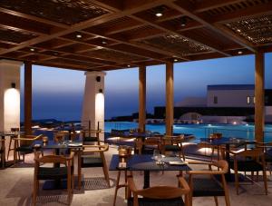 イアにあるSanto Pure Oia Suites & Villasのテーブルと椅子のあるレストラン、プールを提供しています。