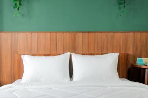 a bed with two white pillows and a wooden headboard at Stay G Service Residence Sentul in Kedungmanggu