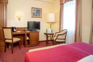 a hotel room with a bed and a desk with a television at Landhotel Zum Hessenpark in Neu-Anspach
