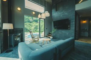 sala de estar con sofá azul y TV en サウナ付き大人の隠れ家 -Kito NASU- en Nasu