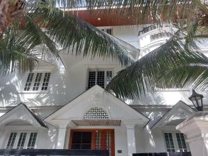 una casa blanca con una palmera delante de ella en annies inn homestay, en Kochi