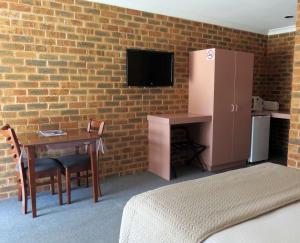 a bedroom with a table and a wall with a tv at The Lydoun Motel in Chiltern