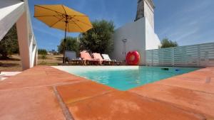 einen Pool mit Sonnenschirm, Tisch und Stühlen in der Unterkunft Casa d´Abela in Abela