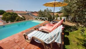 a swimming pool with two deck chairs and an umbrella at Casa d´Abela in Abela