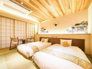 two beds in a room with a table and chairs at 枳殻の杜 Kikoku no mori in Kyoto