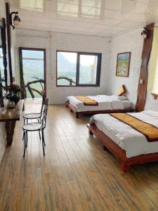 a room with three beds and a table and chairs at Hà Lù Homestay in Lao Cai