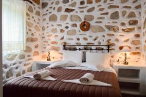 a bedroom with a stone wall with a bed with towels on it at Villa Peristeri in Agios Georgios