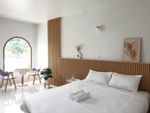 Un dormitorio con una gran cama blanca y una mesa en Ramida House บ้านรมิดา en Ban Sao Thong