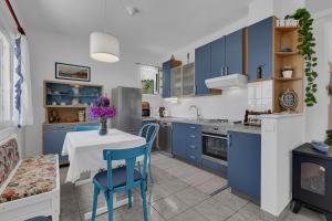 a kitchen with blue cabinets and a table and chairs at Cottage Baskovic in nature park in Makarska