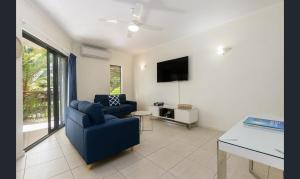 een woonkamer met een blauwe bank en een tv bij Charming 1 bedroom Apt - Close to Town & Beach in Port Douglas