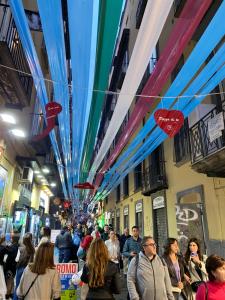 Une foule de gens marchant dans une rue sous des parasols colorés dans l'établissement Three Houses Toledo, à Naples