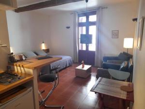 ein Schlafzimmer mit einem Bett und ein Wohnzimmer mit einem Schreibtisch in der Unterkunft Les Studios de St Guilhem in Saint-Guilhem-le-Désert