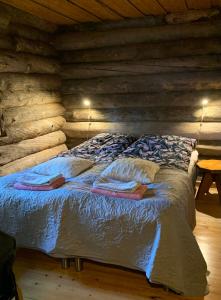 ein Schlafzimmer mit einem Bett in einem Blockhaus in der Unterkunft Logwood Chalet in Luosto