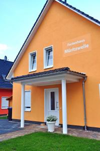 Una casa naranja con un cartel al costado. en Ferienwohnungen Appartements - Ferienhaus Müritzwelle, en Marienfelde