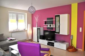 ein Wohnzimmer mit einem lila Stuhl und einem TV in der Unterkunft Ferienwohnungen Appartements - Ferienhaus Müritzwelle in Marienfelde
