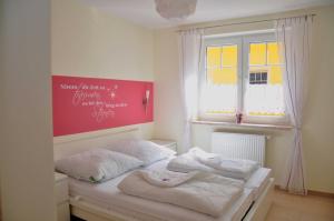 Un dormitorio con una cama con sábanas blancas y una ventana. en Ferienwohnungen Appartements - Ferienhaus Müritzwelle, en Marienfelde