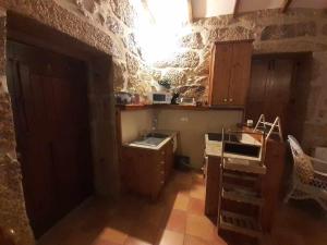 a kitchen with a stone wall with a sink and cabinets at Casas do Minério in Guarda