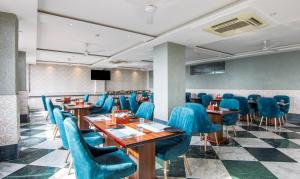 a restaurant with blue chairs and tables and a screen at Treebo Trinetar International in Jammu