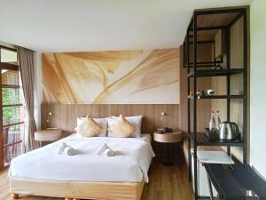a bedroom with a large white bed with a wooden wall at Issara Boutique Winery Hotel in Muak Lek District