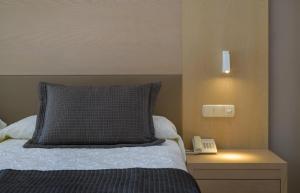 a bed with a pillow and a phone on a night stand at Hipotels Natura Palace Adults Only in Playa Blanca