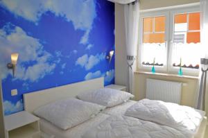 un dormitorio con una pared azul con nubes pintadas en él en Ferienwohnungen Appartements - Ferienhaus Müritzlust, en Marienfelde