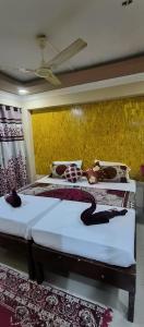 sypialnia z 2 łóżkami i żółtą ścianą w obiekcie ALEGRO HOLIDAY HOMES w mieście Palolem