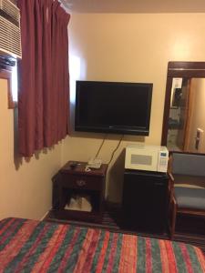 a bedroom with a bed and a tv and a table at Budget Inn - Cambridge in Fairdale