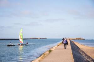 un grupo de personas caminando por un muelle con un velero en La Maison du Bastion - Gravelines centre, en Gravelines