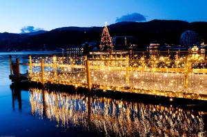a pier with christmas lights and a christmas tree at Parkhotel Pörtschach - Das Hotelresort mit Insellage am Wörthersee in Pörtschach am Wörthersee