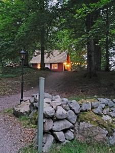 una cabaña de madera en el bosque con una pared de piedra en Blueberry Hill en Skånes Fagerhult