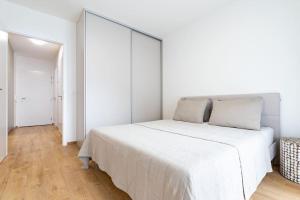 a white bedroom with a large white bed in it at Apartmán Al-Park s private parking, 5 min pešo do centra in Košice