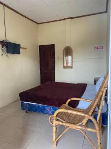 a room with a bed and a chair in it at RON'S Guest House Berastagi Backpacker Rooms in Berastagi
