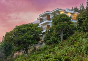 a building on the side of a hill with trees at Sleeping Beauty by Nature Resorts in Coonoor